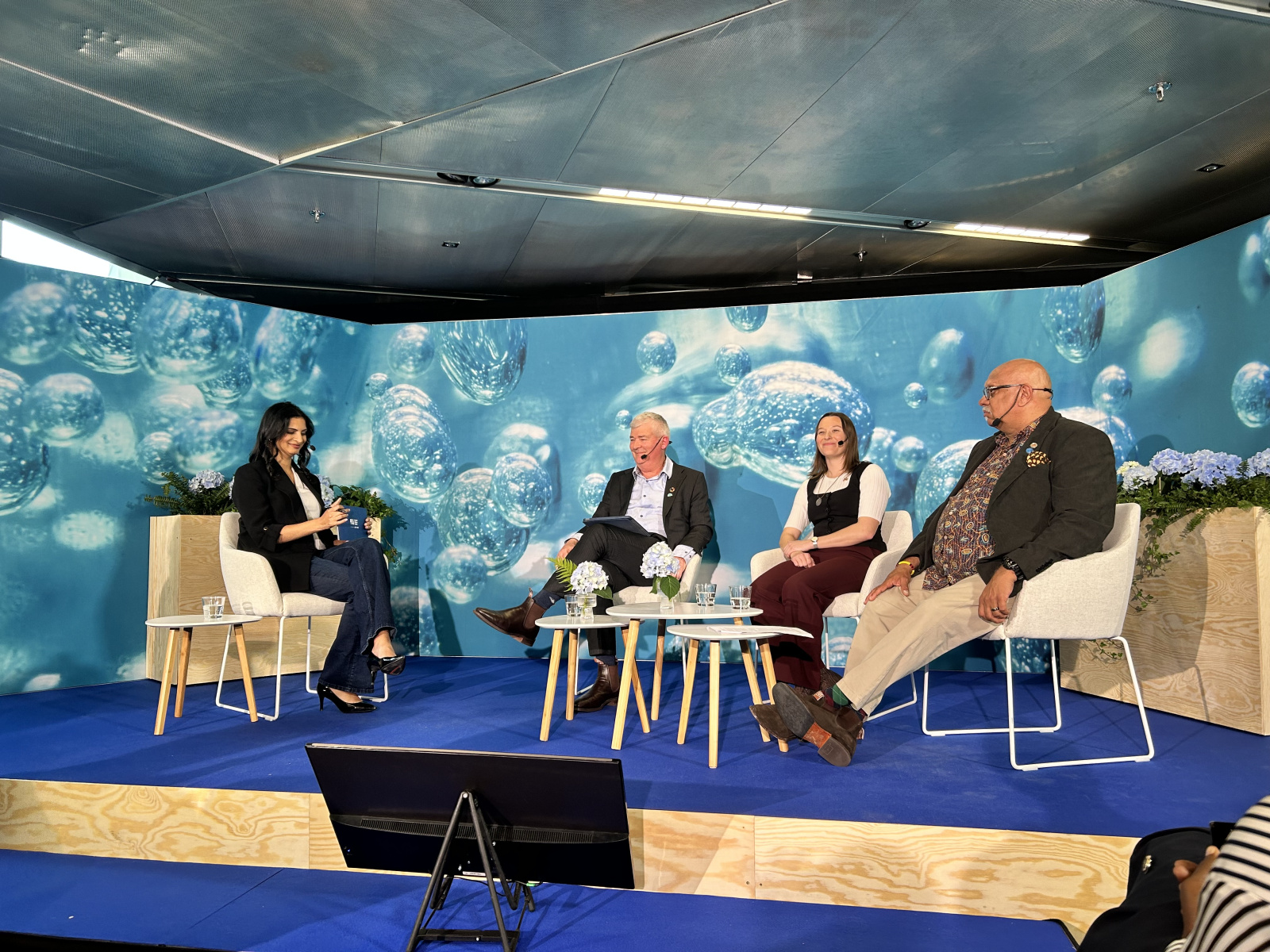 A panel of 4 people on stage with a blue background