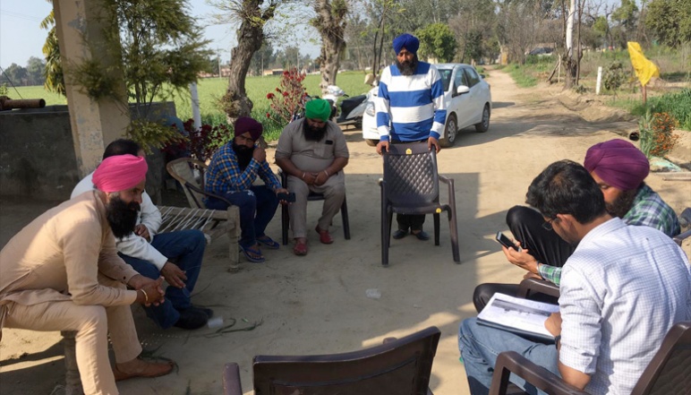Mohan speaking with farmers in circle