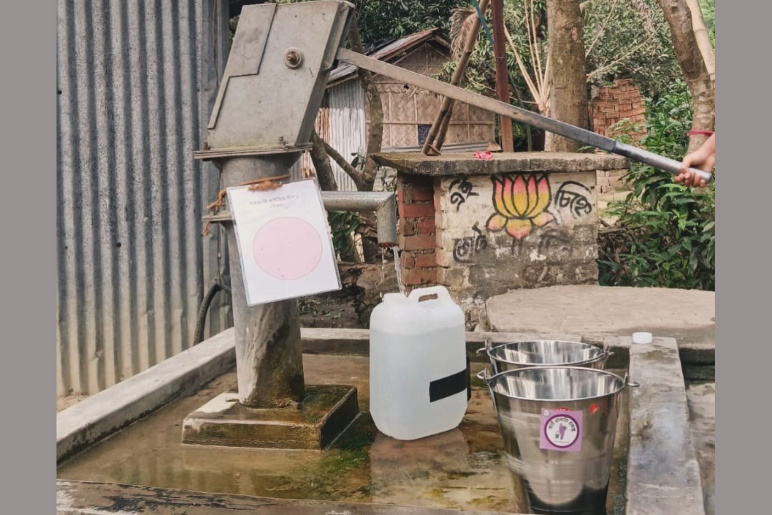 A plastic jug of water and a metal bucket by a well in India