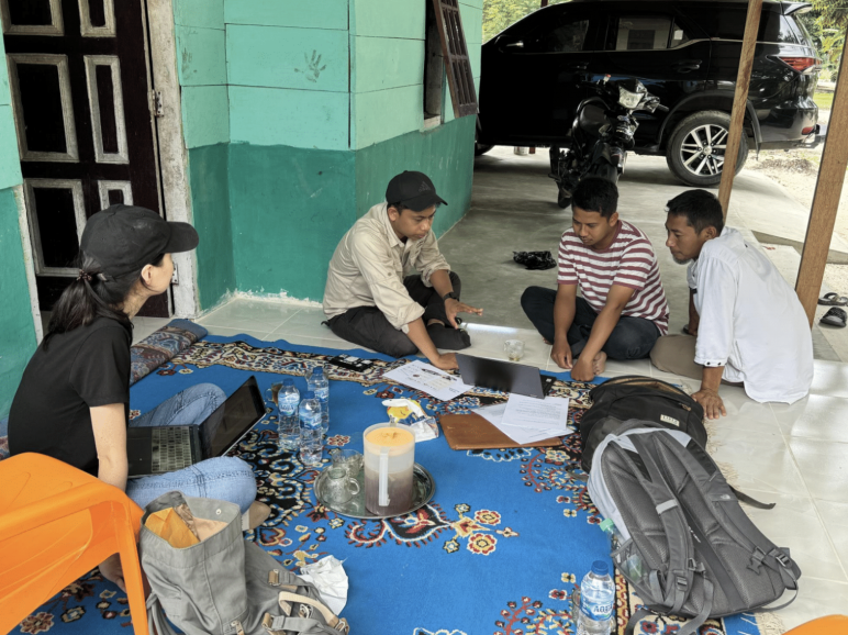 Four people sitting on the ground in discussion