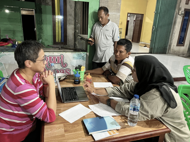 Yanchong (Karen) Zheng sitting at a table with three stakeholders looking at a computer
