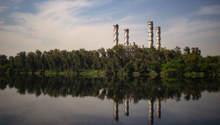 A factory surrounded by tree and next to a river