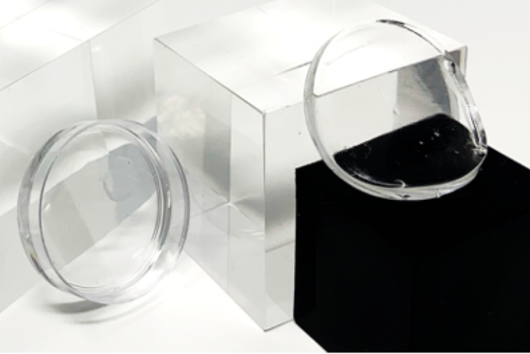 A close-up of transparent optical components placed on reflective surfaces in a laboratory.