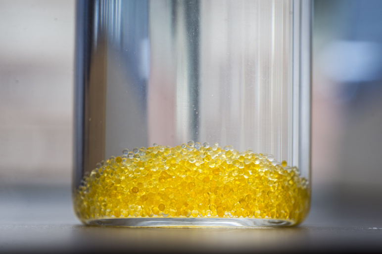 a close up of a glass jar containing water and yellow hydrogel beads at the bottom