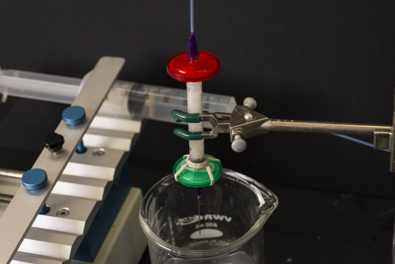 Glass lab beaker and metal clamp amongst other lab experiment looking equipment
