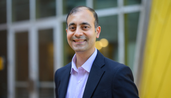 Karnik is smiling in front of a blurred background. 