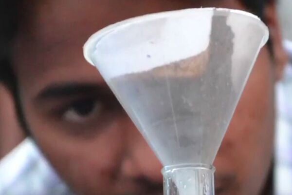 Indian man looking at soil in a funnel