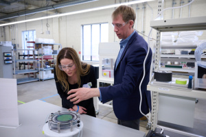 Two individuals wearing PPE standing in a laboratory setting