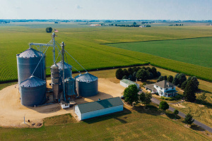 Various gray silos and a house on a large agricultural plot. 