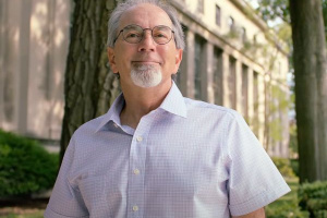 John Lienhard in a white button down shirt standing outside an MIT building