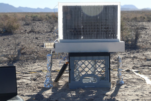 A black panel with machinery underneath set up in a desert-like environment