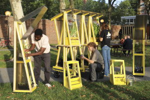 Three people outside setting up mobile farming devices