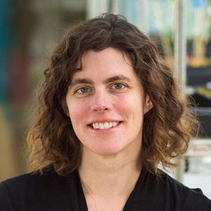 Women with shoulder-length curly brown hair smiles