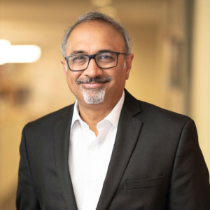 Sanjay Sarma stands in a white shirt and black suit coat