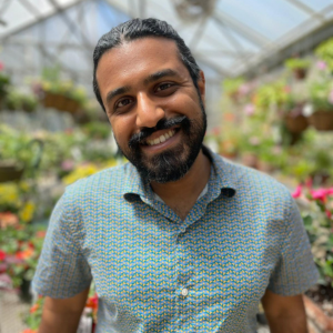 Gokul Sampath, standing inside a green house, with a dark beard
