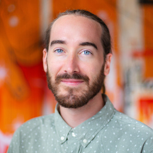 A portrait of an individual against an orange background.