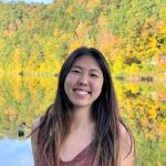 Photo of Adela Li in front of a pond and green and yellow trees