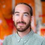 A portrait of an individual against an orange background. 