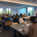 Multiple people sitting at tables in the conference room at a workshop
