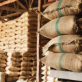 stacks of brown burlap sacks of rice in a warehouse